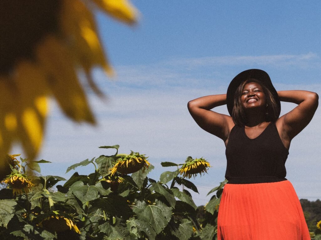 Mulher negra sorrindo no sol em um campo de girassóis